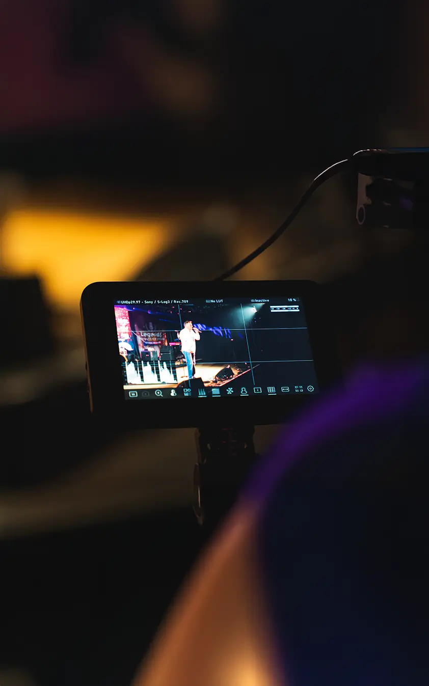 Person filmt einen Live-Auftritt über den Kameramonitor bei einer Videoproduktion