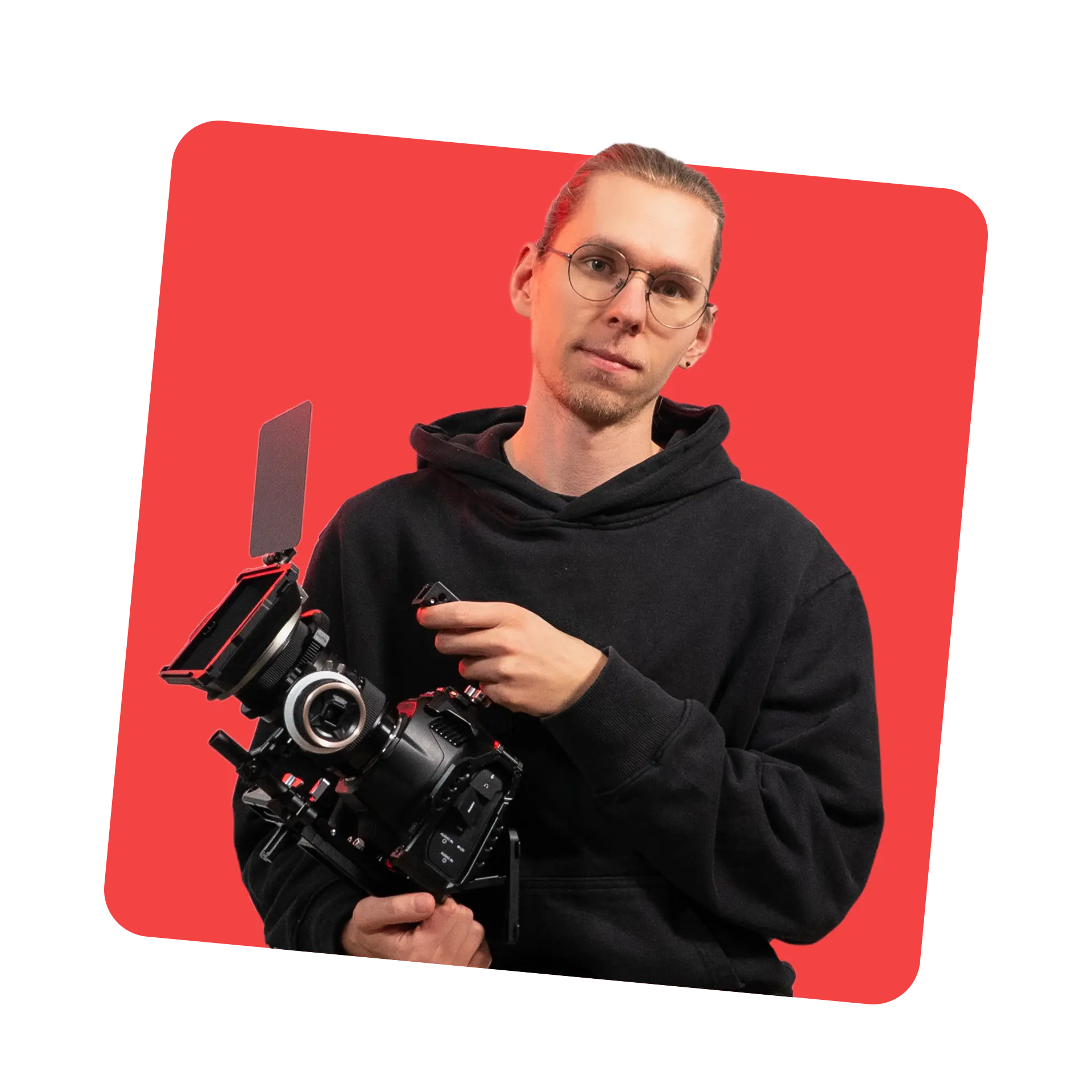 Lennard Mertens im schwarzen Hoodie hält eine Cinema-Kamera vor rotem Hintergrund